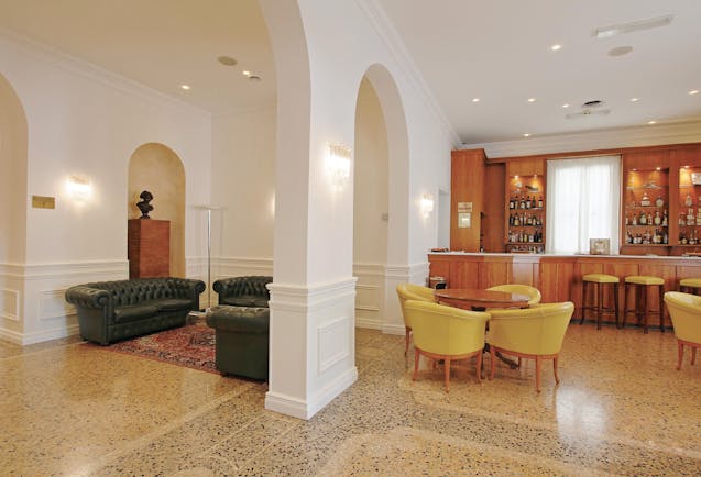 Rechigi Park Hotel bar, bright elegant decor, tiled floors, wooden bar, chairs, leather sofa, archway