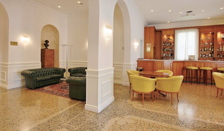 Rechigi Park Hotel bar, bright elegant decor, tiled floors, wooden bar, chairs, leather sofa, archway