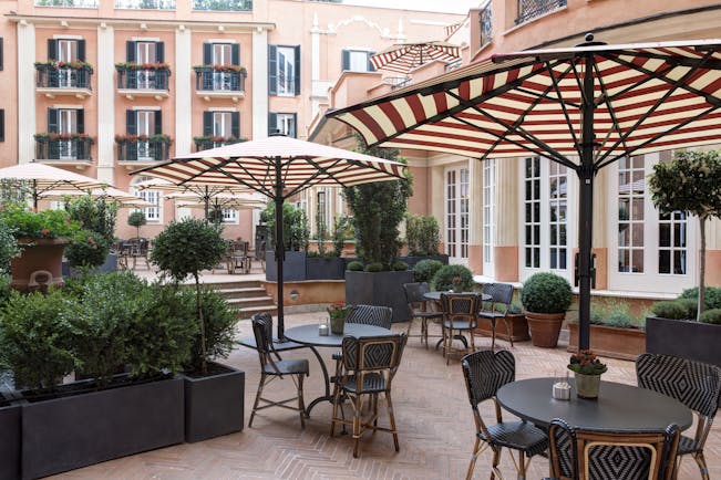 Hotel de la Villa Rome outdoor seats with red and white parasols