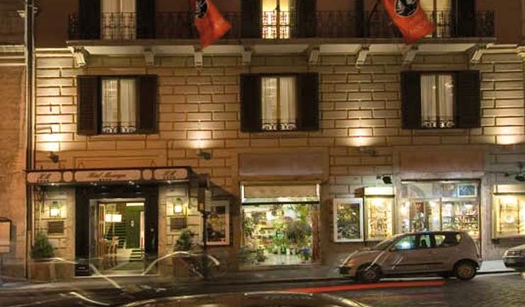 Exterior of hotel with flags outside and shutters on the windows