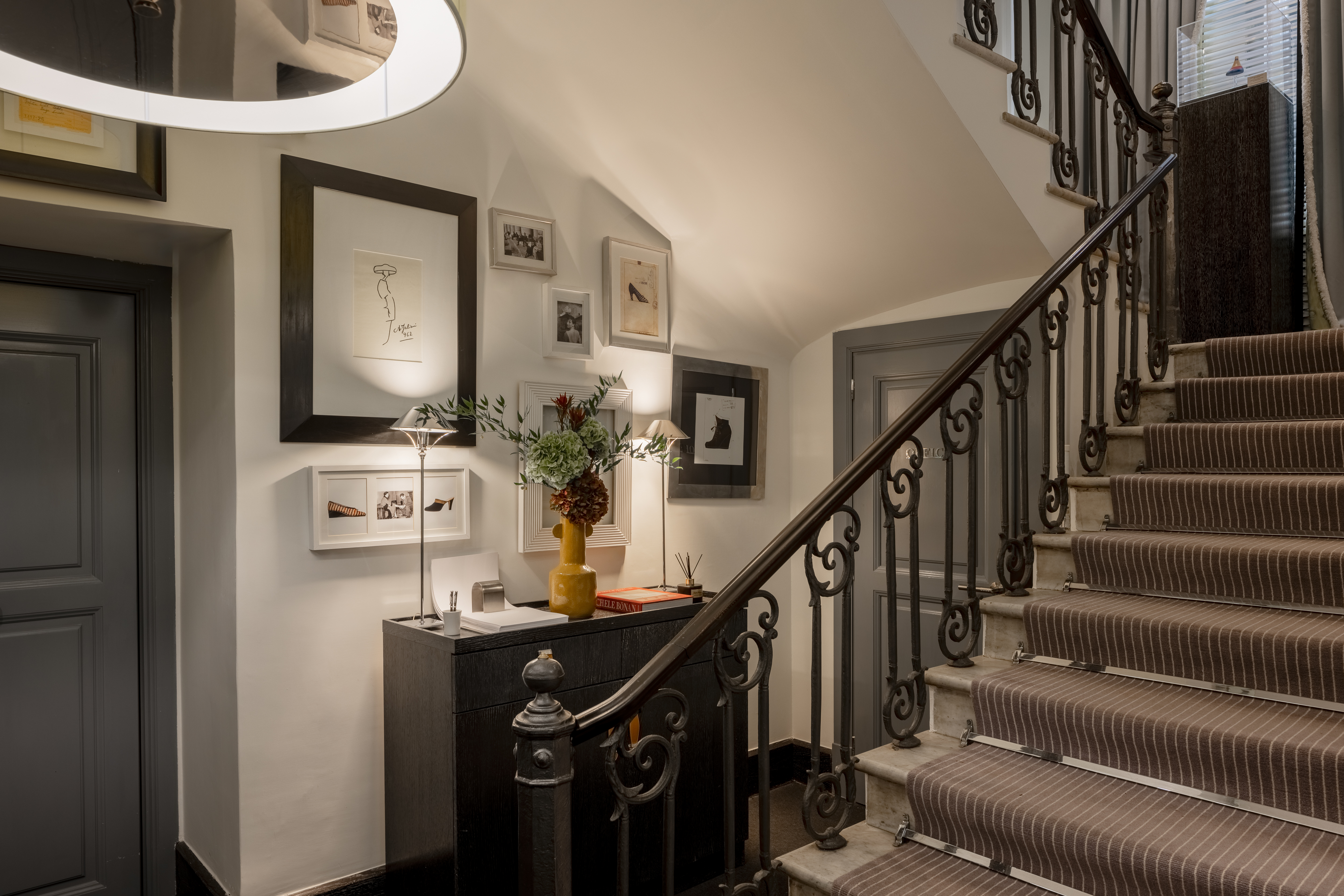Hotel Portrait Roma interior stairs, with many photographs and sketches on the walls and a grey-themed colour palette