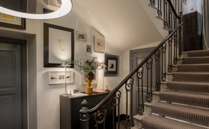 Hotel Portrait Roma interior stairs, with many photographs and sketches on the walls and a grey-themed colour palette