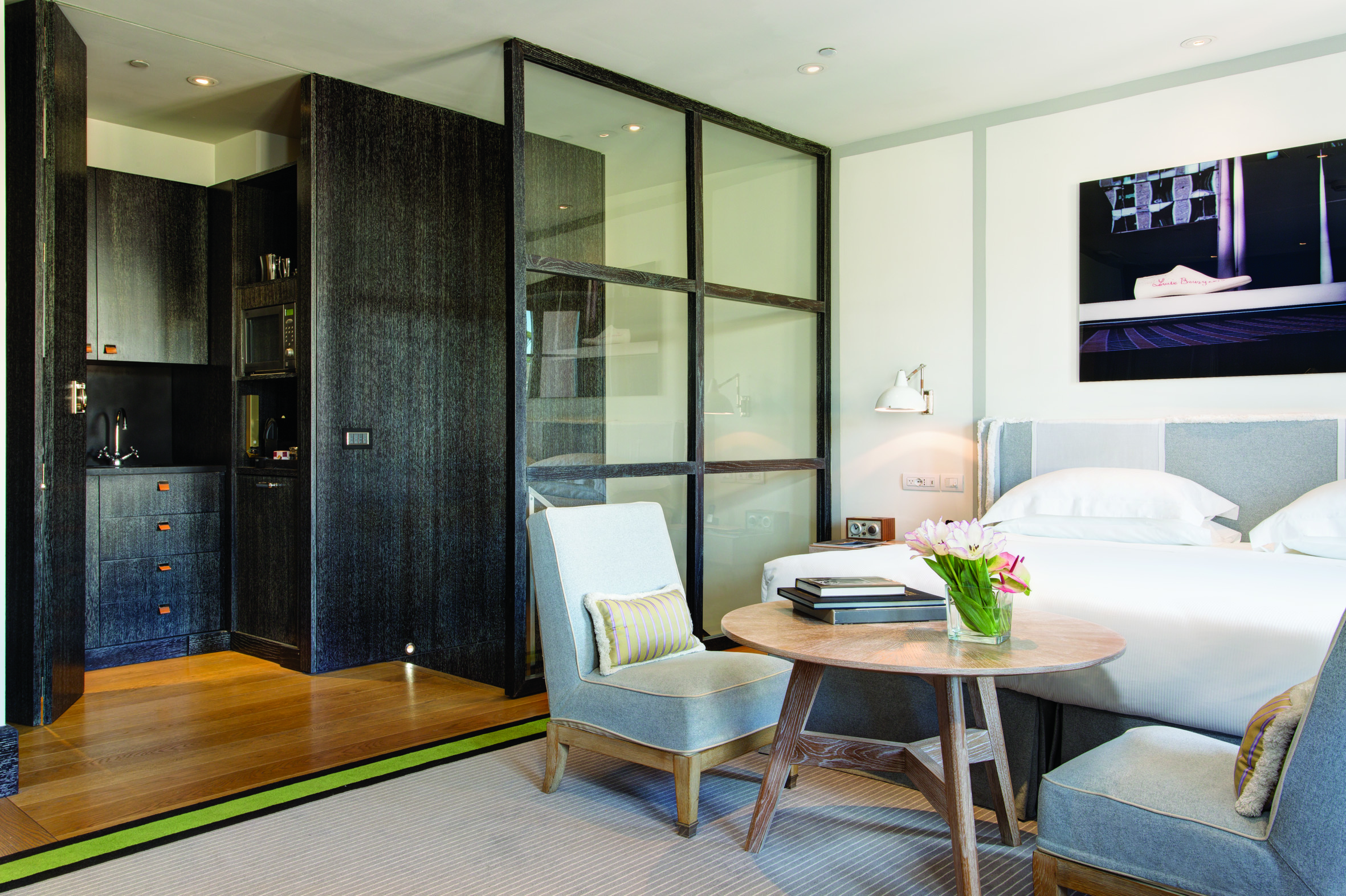 Hotel Portrait Roma Studio Deluxe with white, grey, and light wood decor, with kitchenette, double bed, and small seating area