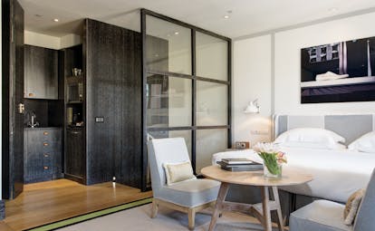 Hotel Portrait Roma Studio Deluxe with white, grey, and light wood decor, with kitchenette, double bed, and small seating area