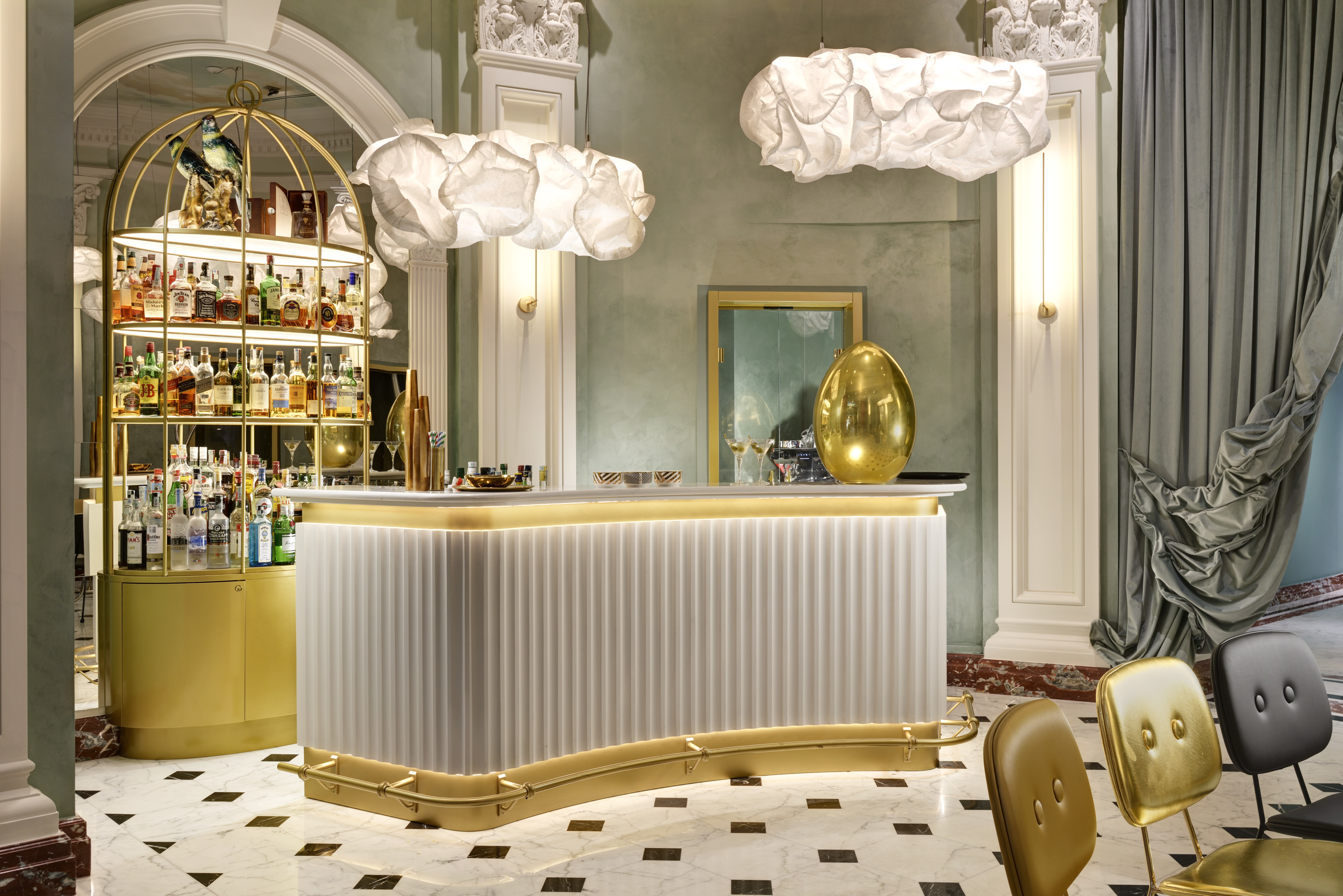 Leon's Place bar, with light gold trim, gold, bronze, and black chairs, and a drinks cabinet that resembles a birdcage