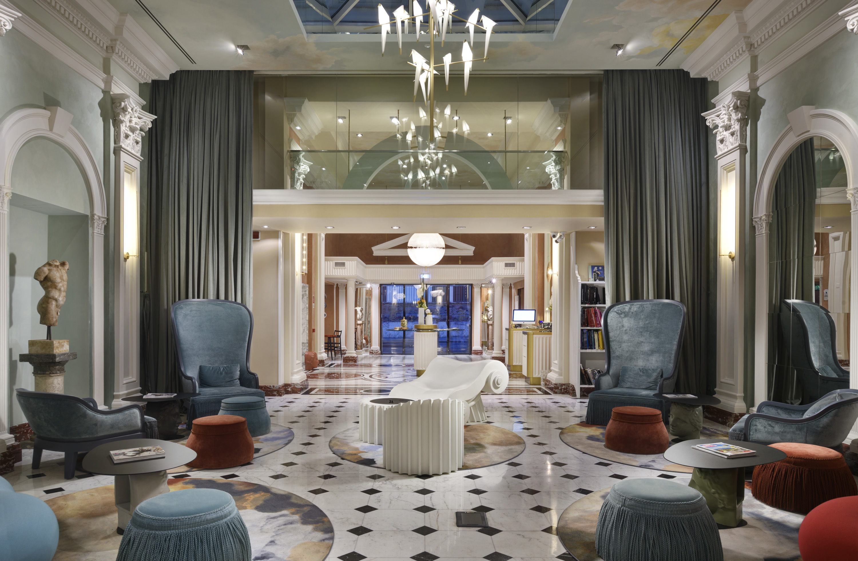 Leon's Place lounge, with exaggeratedly high-backed armchairs, patterned floor tiles, high frescoed ceilings, arched doorways, and artistic decorations