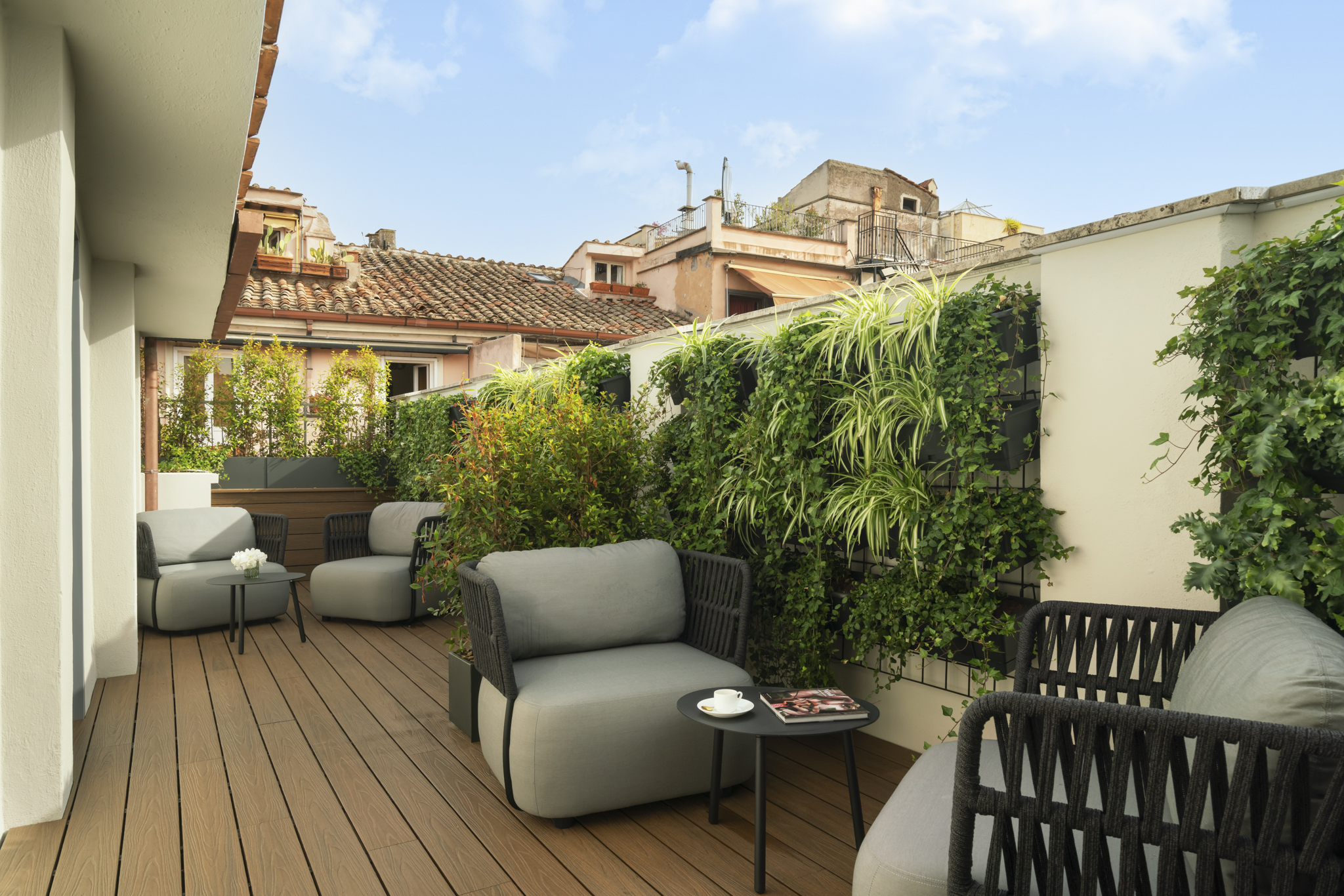 Palazzo Venere terrace with decked floor, stone vine-covered walls, soft furnishings and blue skies above