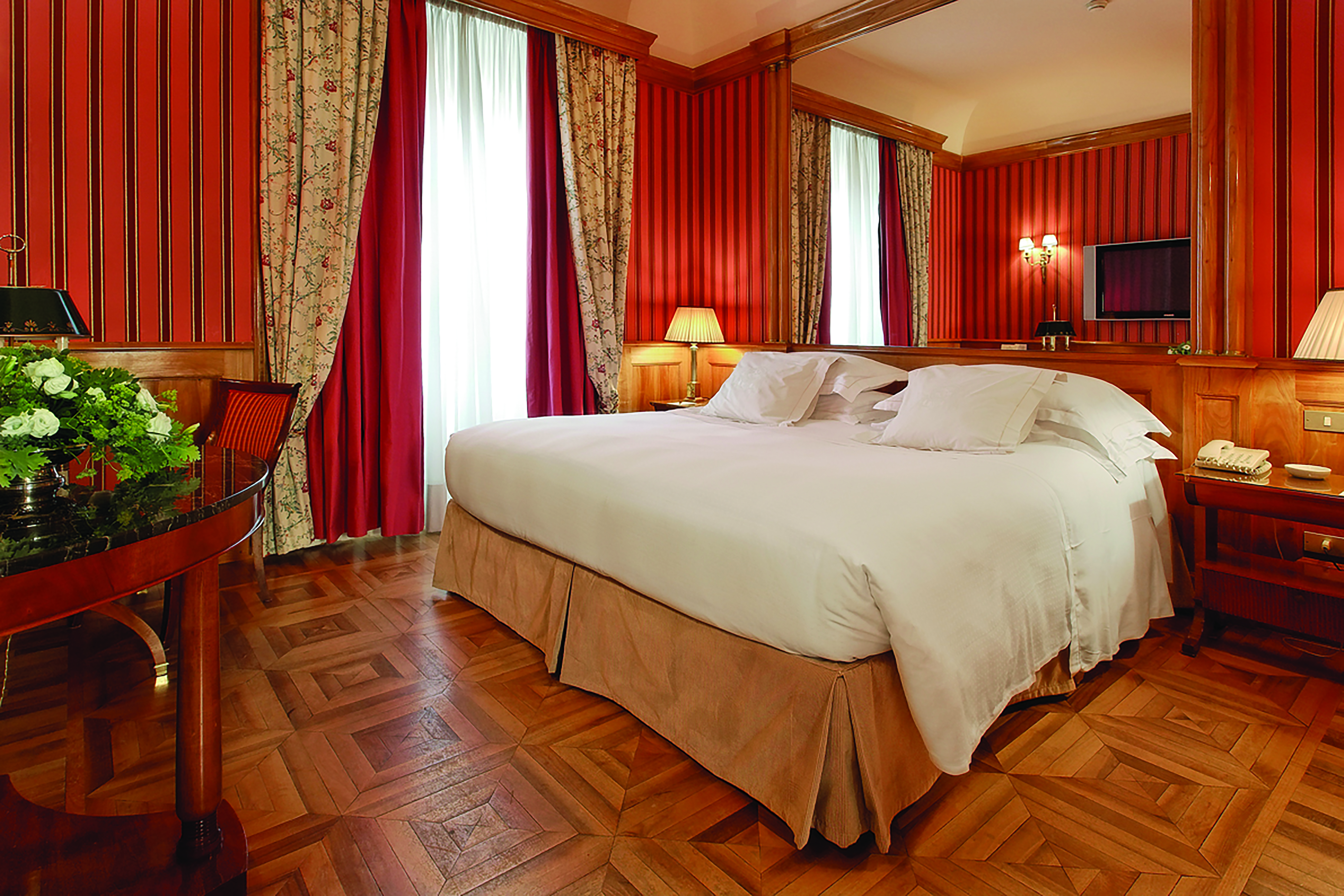 Deluxe room with wooden parquet floor and red wallpaper at the Grand Hotel Sitea Turin