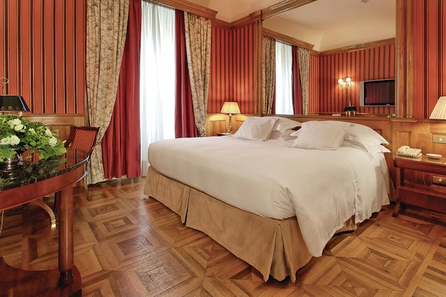 Deluxe room with wooden parquet floor and red wallpaper at the Grand Hotel Sitea Turin