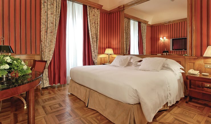 Deluxe room with wooden parquet floor and red wallpaper at the Grand Hotel Sitea Turin