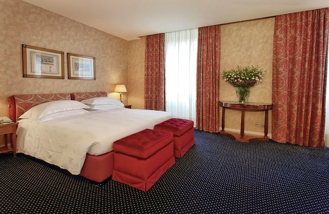 Double bedroom with red curtains and blue carpet at the Grand Hotel Sitea Turin