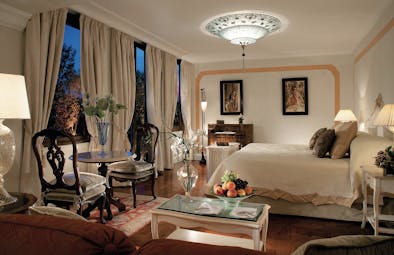 Belmond Hotel Cipriani suite with a king sized bed, cream and beige colour scheme, a chandelier and paintings on the walls