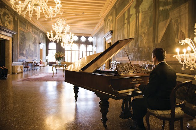 Ca Sagredo Venice Portego hall fresco candelabra man playing baby grand piano