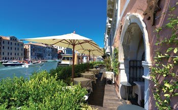 Ca Sagredo Venice terrace outdoor seating area overlooking canal dining tables umbrellas