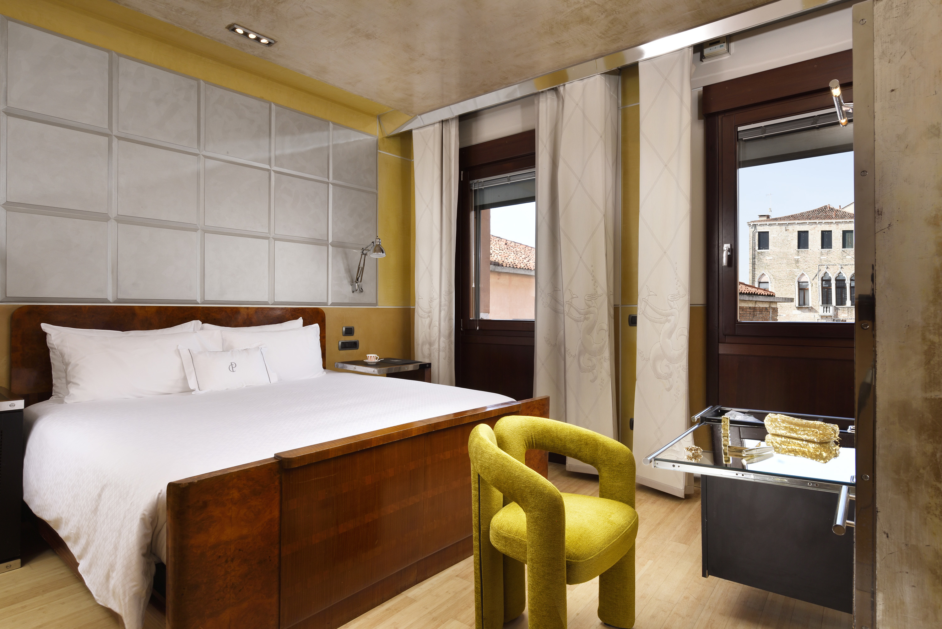 Ca' Pisani Executive Room with neutral tones against touches of bright yellow, and two windows looking out on Venice
