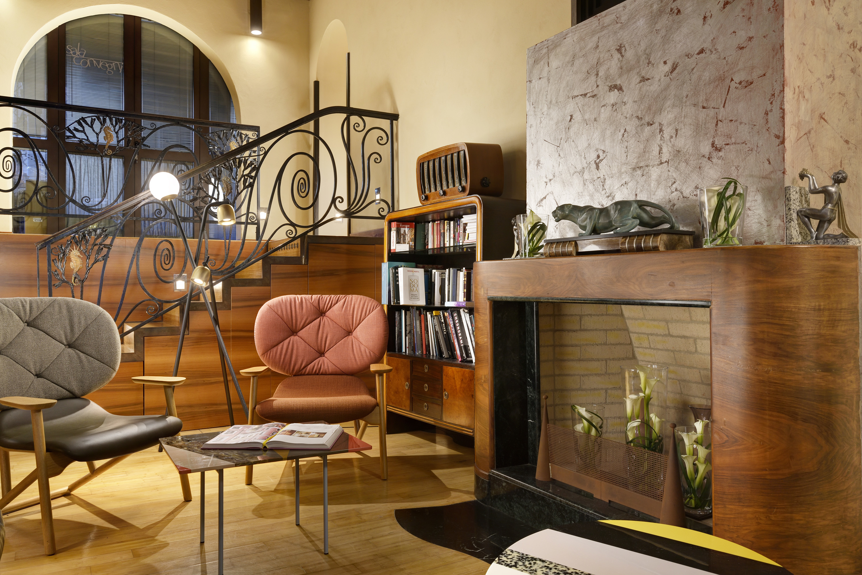 Ca' Pisani lounge area, with wood and stone fireplace, plush chairs, and stairs with wrought iron banisters behind