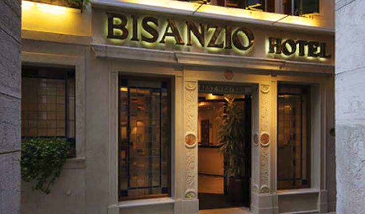 Entrance to the Bisanzio Hotel with the sign lit up in black above the wooden door
