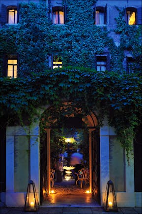 Entrance to Hotel Flora at dusk with vines creeping up the hotel walls and a large arch doorway