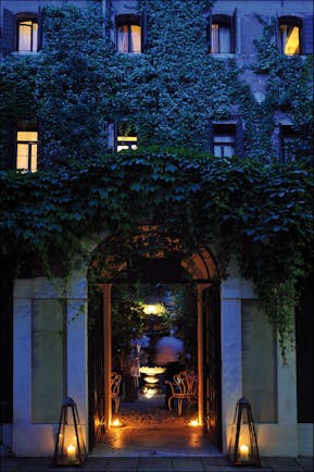 Entrance to Hotel Flora at dusk with vines creeping up the hotel walls and a large arch doorway