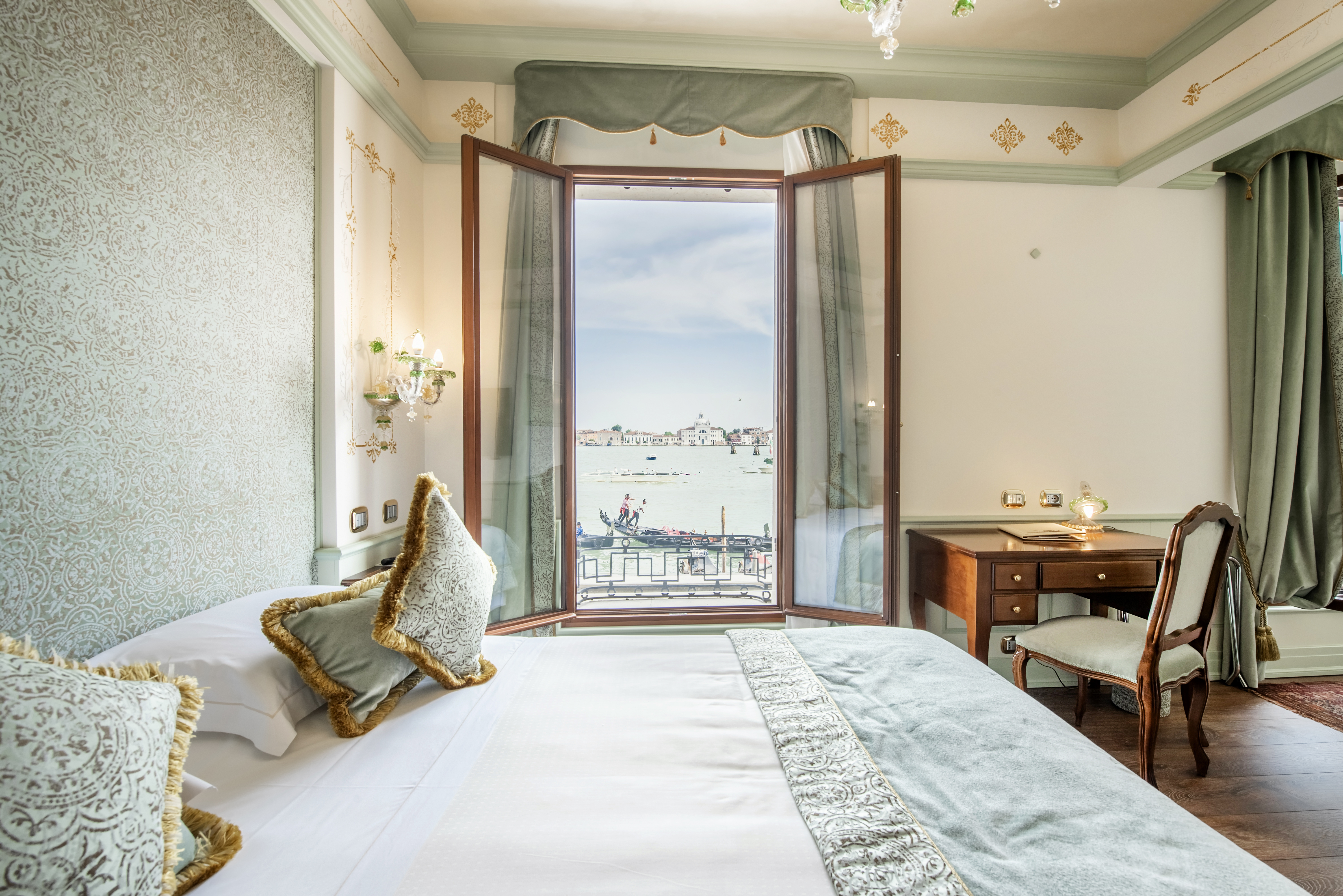 Hotel Monaco & Grand Canal Deluxe Room, as seen across the pale green and gold bed, with views through open windows onto the Grand Canal