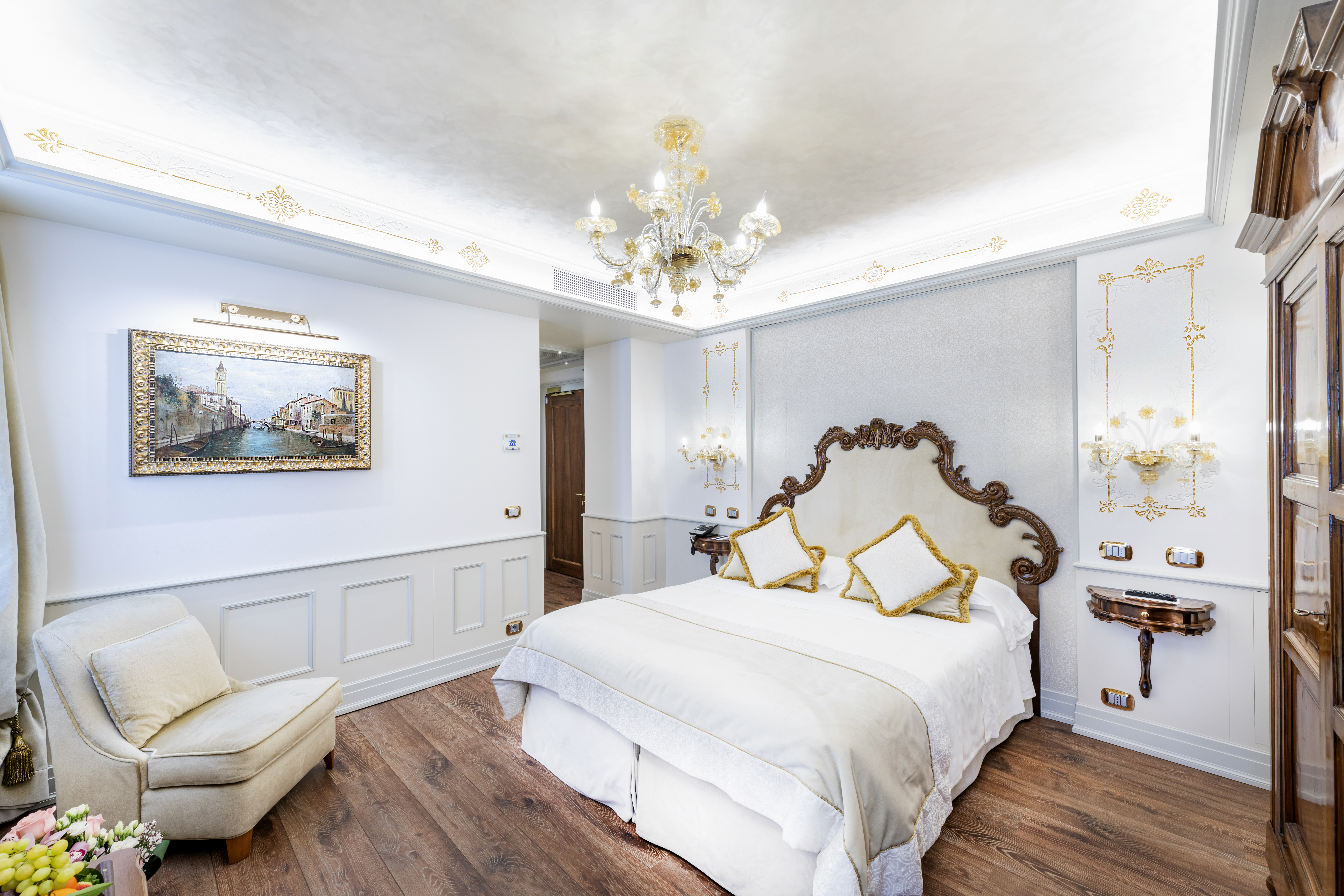 Hotel Monaco & Grand Canal Superior Room with ornate darkwood bedframe, white and pale gold sheets and pale blue decor