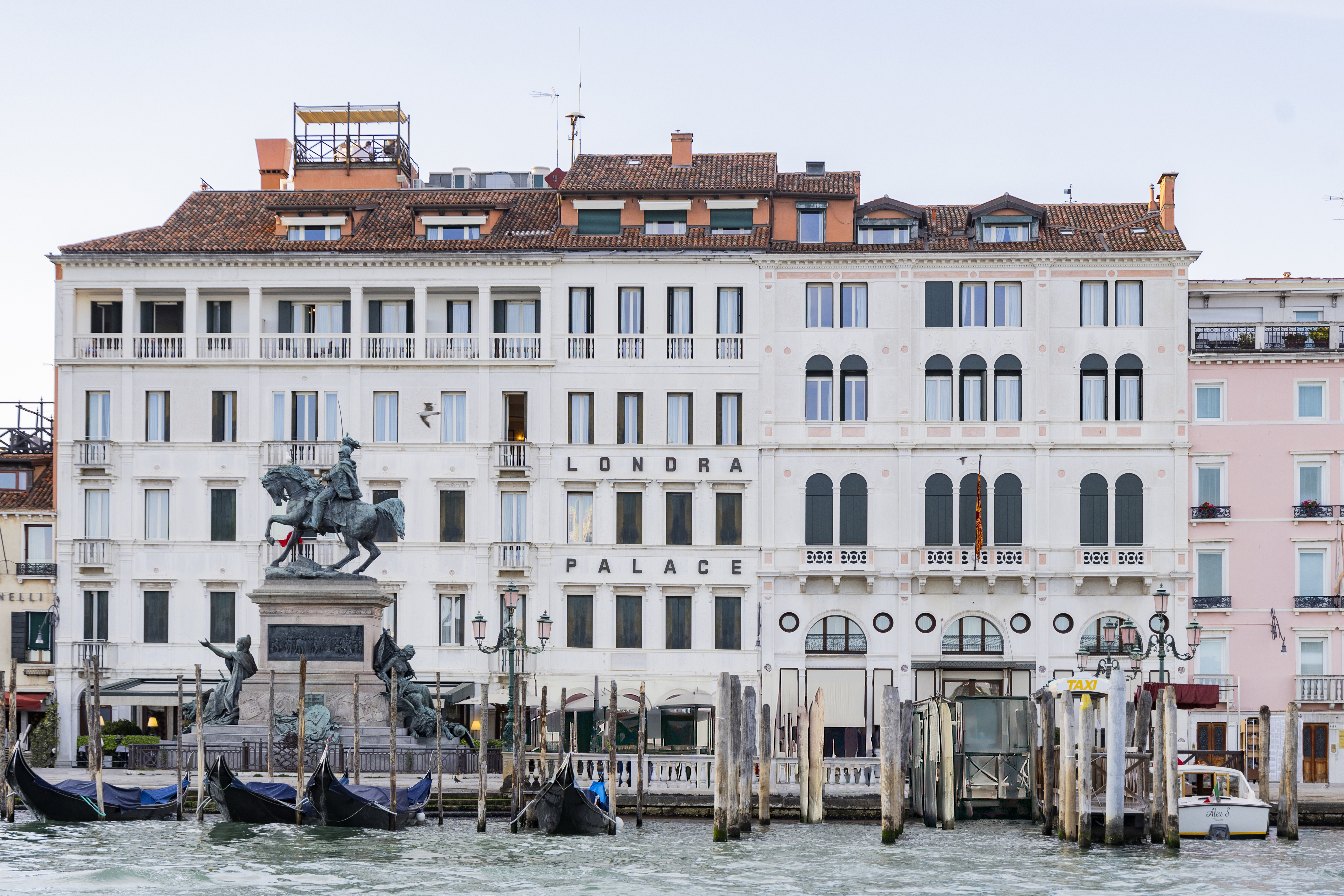 Londra Palace Venezia exterior, with tall palatial facade on the banks of a canal, white walls, and gondolas in the foreground