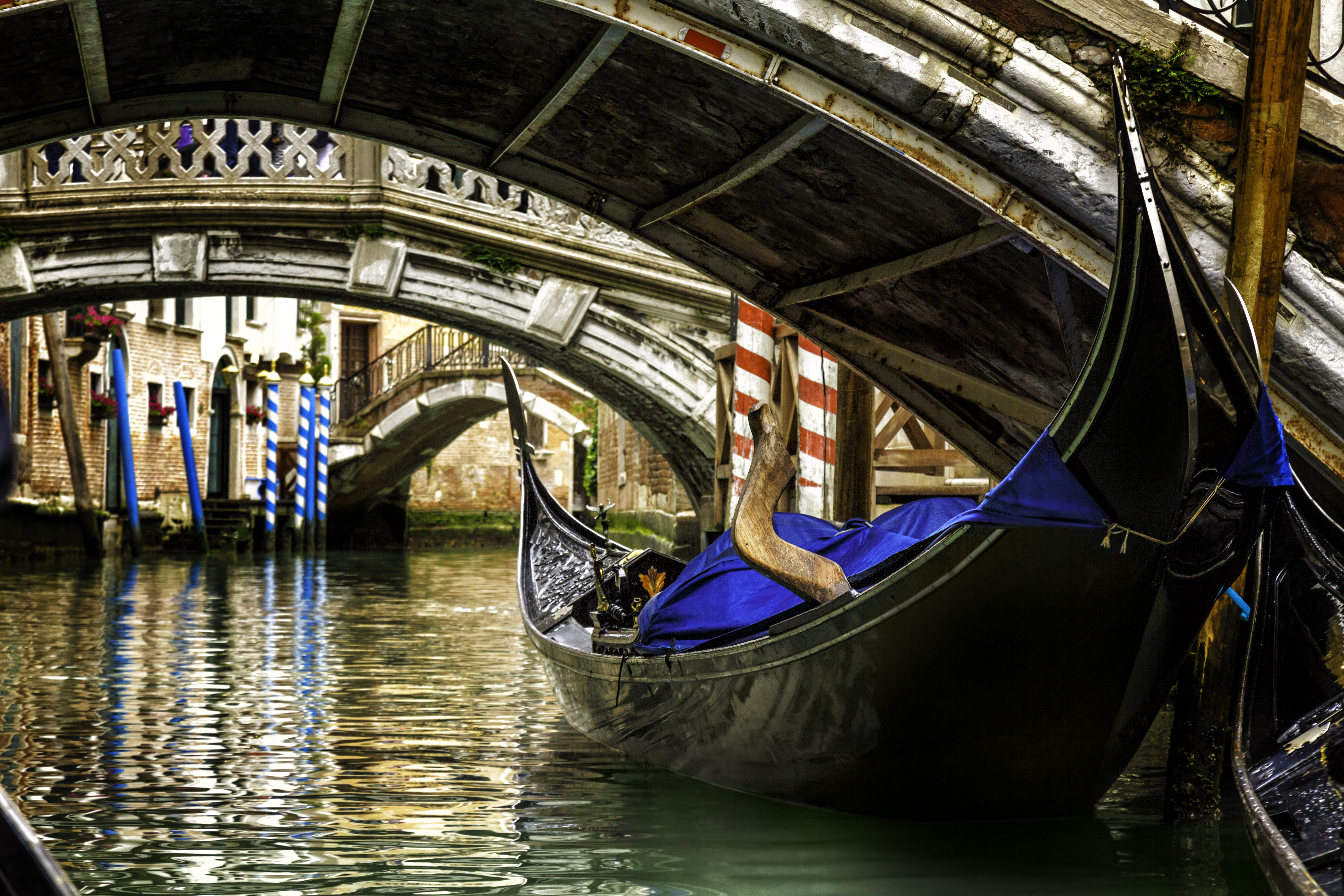 Gondola under low bridge in Venice with reflections on water