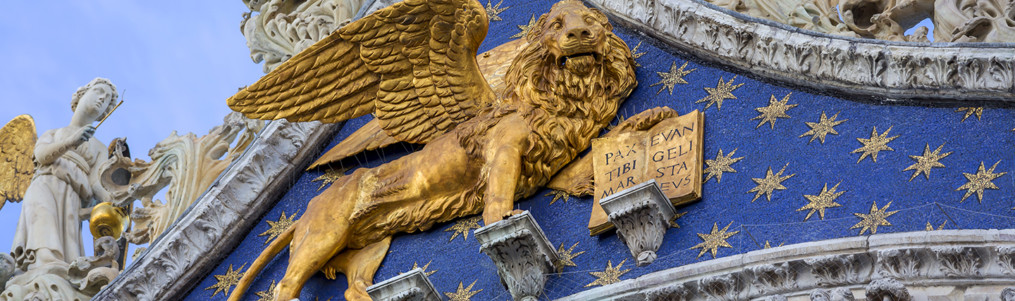 Golden lion statue on front of ornate blue and golden starred facade in Venice