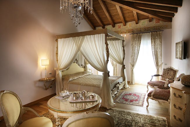 Bedroom with four poster bed with drapes, curtains and chandelier