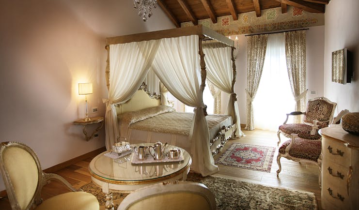 Bedroom with four poster bed with drapes, curtains and chandelier