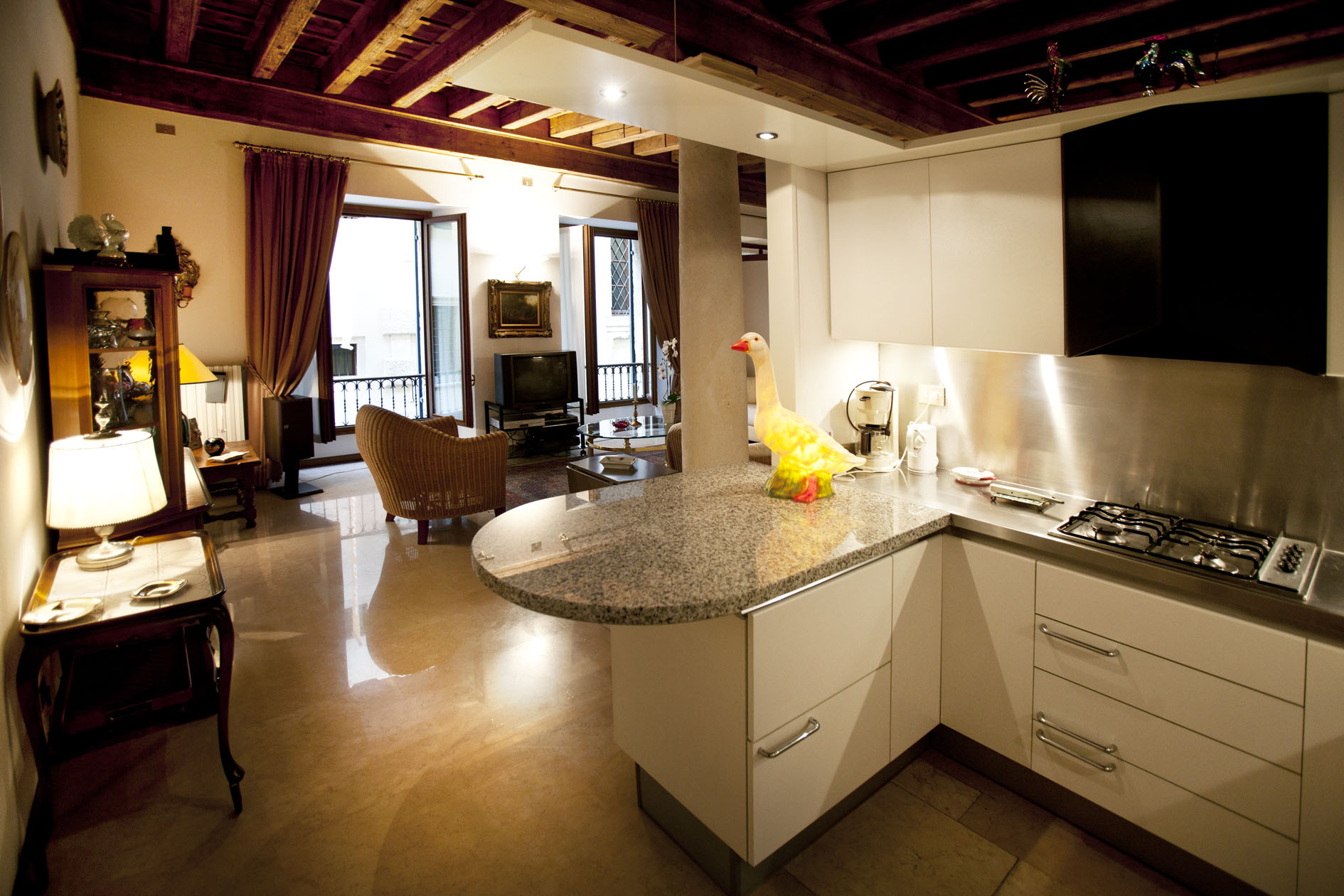 Kitchen suite with cooking equiptment, living area and doors opening onto balcony