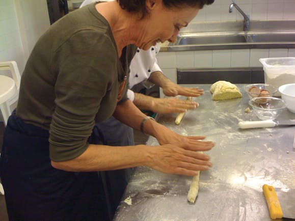 Lady rolling pasta on a table