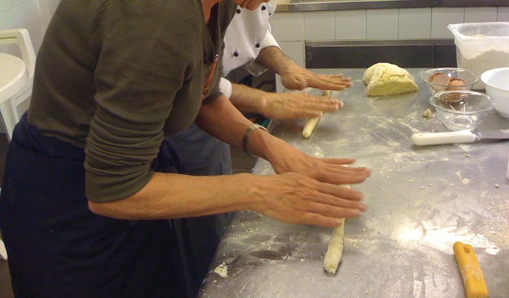 Lady rolling pasta on a table