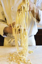 Chef in whites holding strands of freshly made tagliolini
