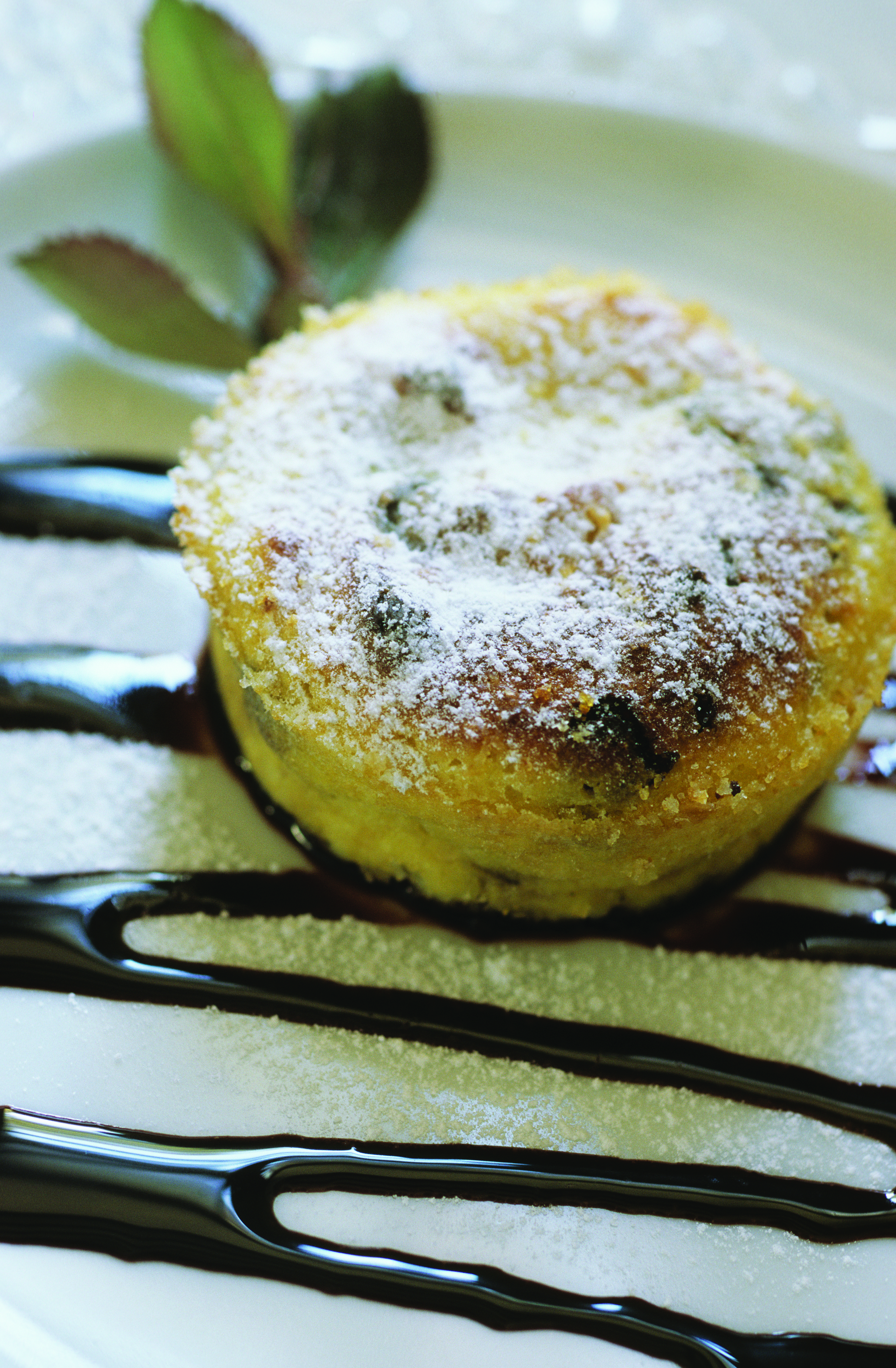 Sugar coated round cake pudding on white plate with chocolate
