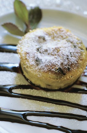 Sugar coated round cake pudding on white plate with chocolate