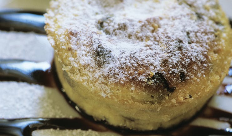 Sugar coated round cake pudding on white plate with chocolate