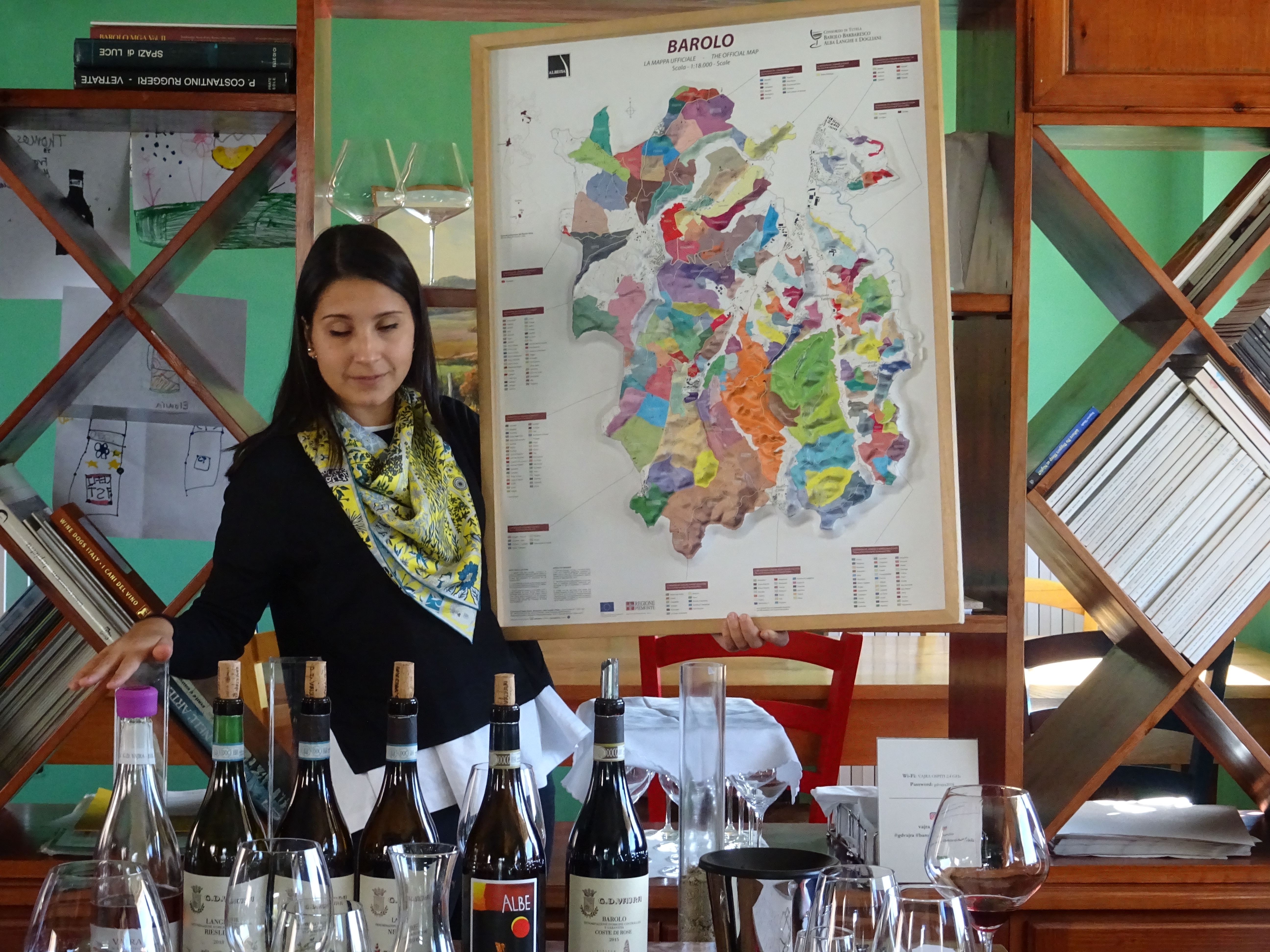 Lady showing map of terroir and wine bottles on table