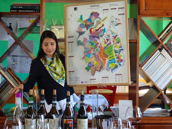 Lady showing map of terroir and wine bottles on table
