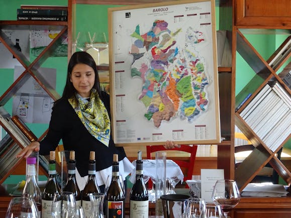 Lady showing map of terroir and wine bottles on table