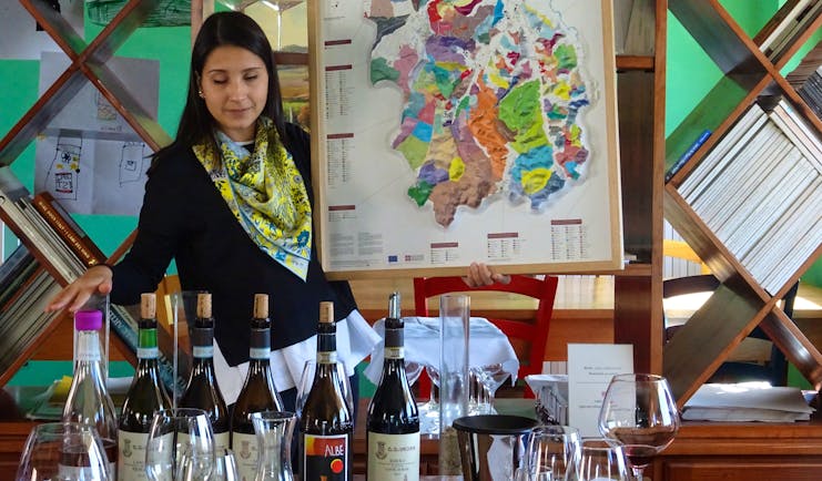 Lady showing map of terroir and wine bottles on table