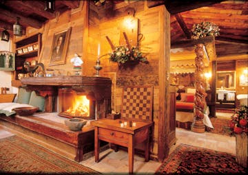 Suite with wood pannelled walls, paintings on the walls, an open fireplace, bedroom and old fashioned decor