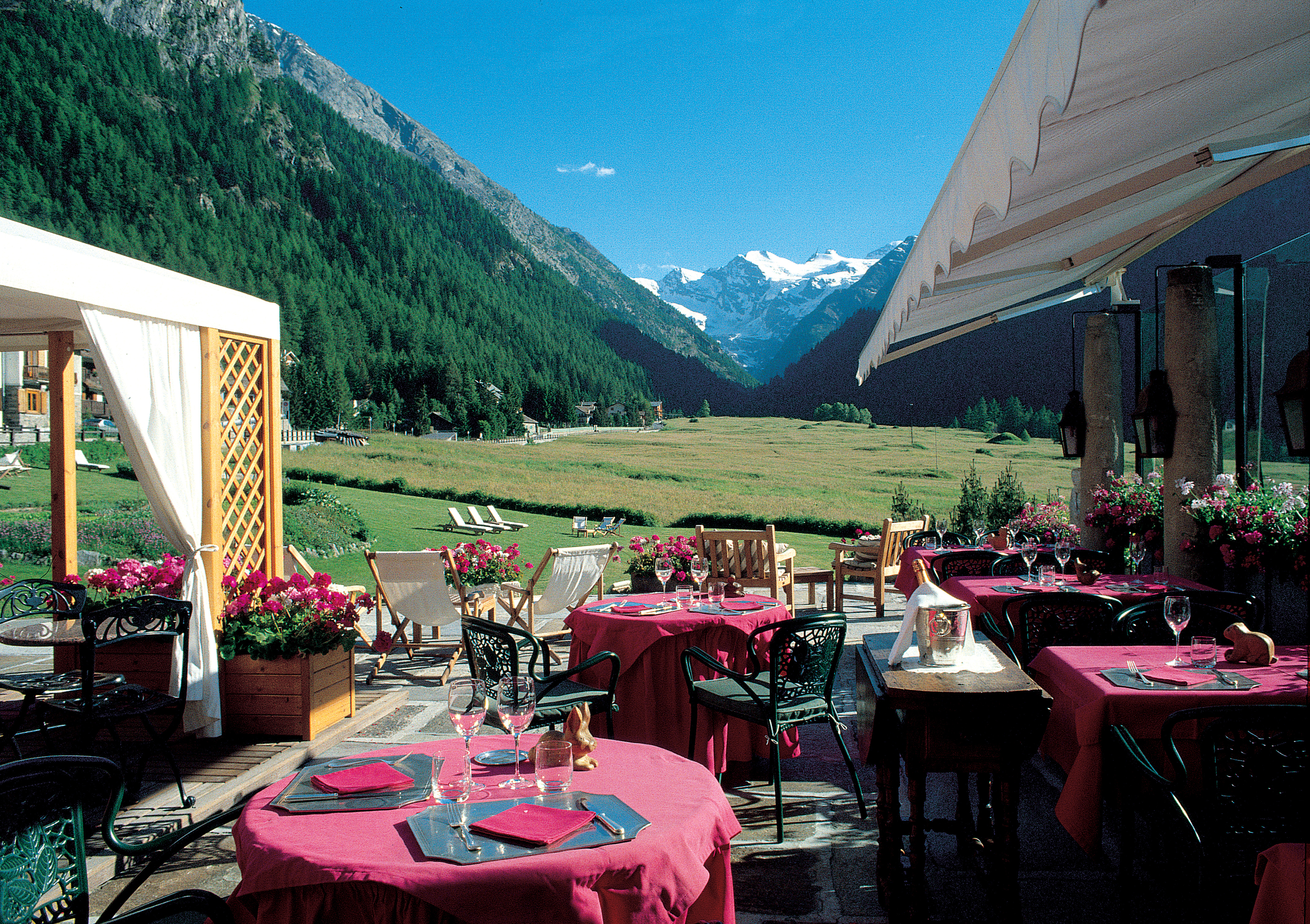 Outdoor dining terrace with views of snowy peaks and tables and chairs set out ready for a meal