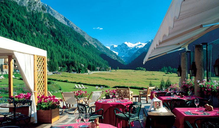 Outdoor dining terrace with views of snowy peaks and tables and chairs set out ready for a meal