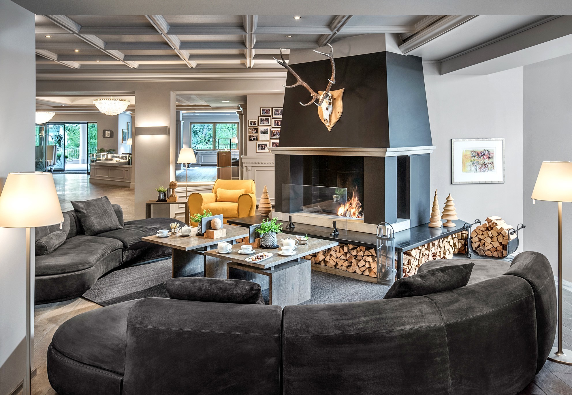 Garden Grodnerhof loung area with central fireplace, large curved sofas, and other sitting areas visible through archways on the far side of the room