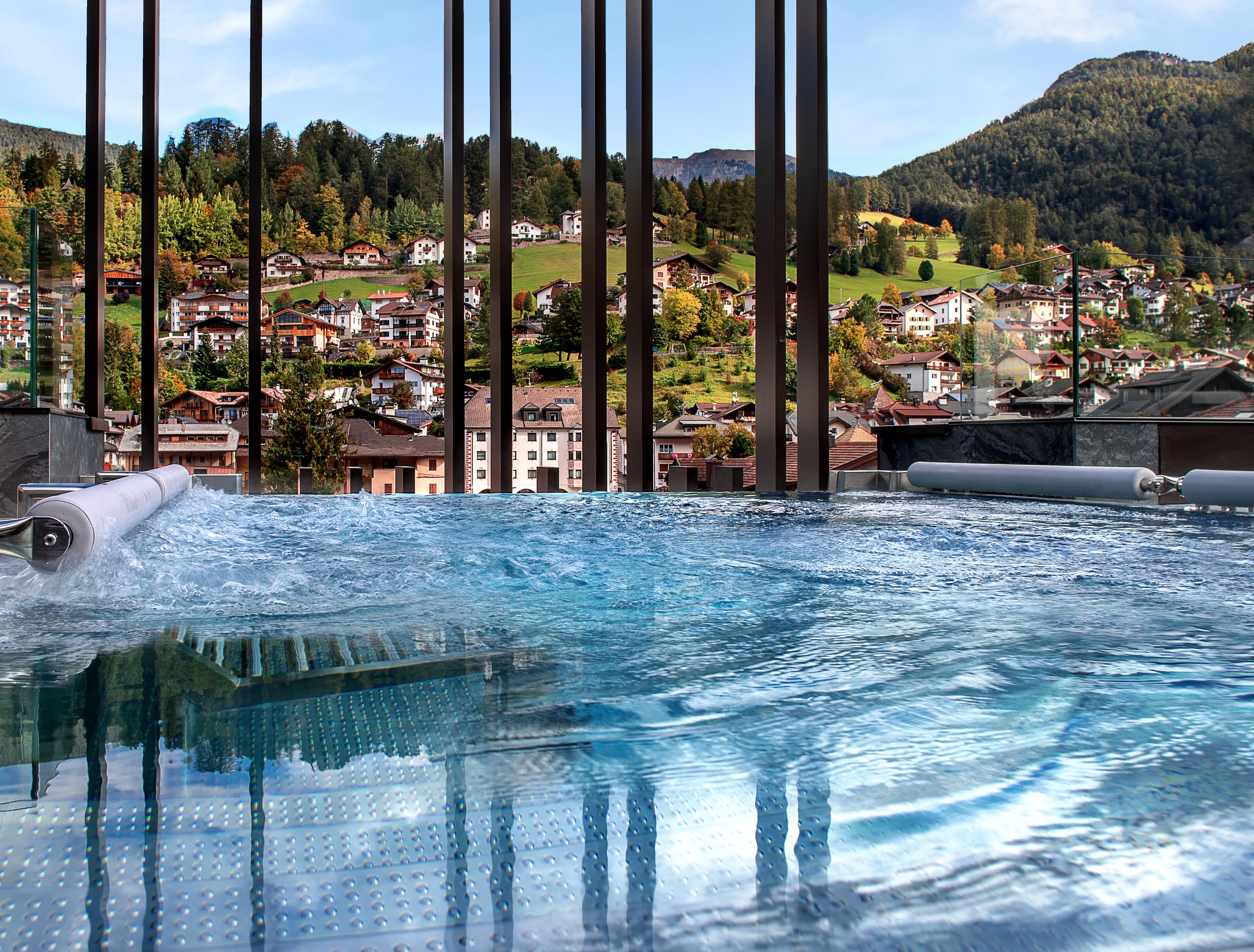 Gardena Grodnerhof pool close-up, showing the waterfall aspect, with the village and green scenery in the background