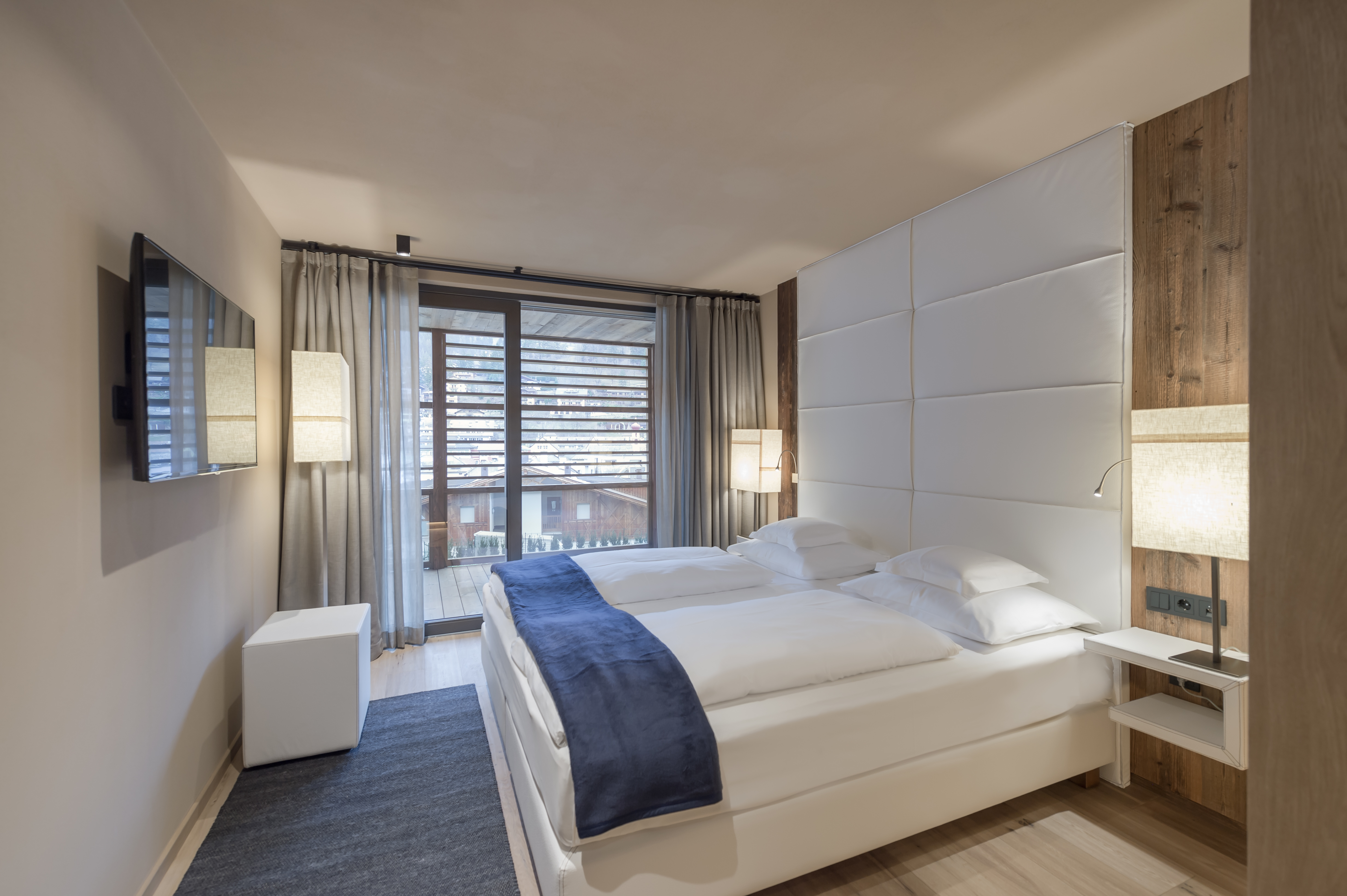 Gardena Grodnerhof room, with twin beds with white linen, wood touches for authentic chalet style, and double doors