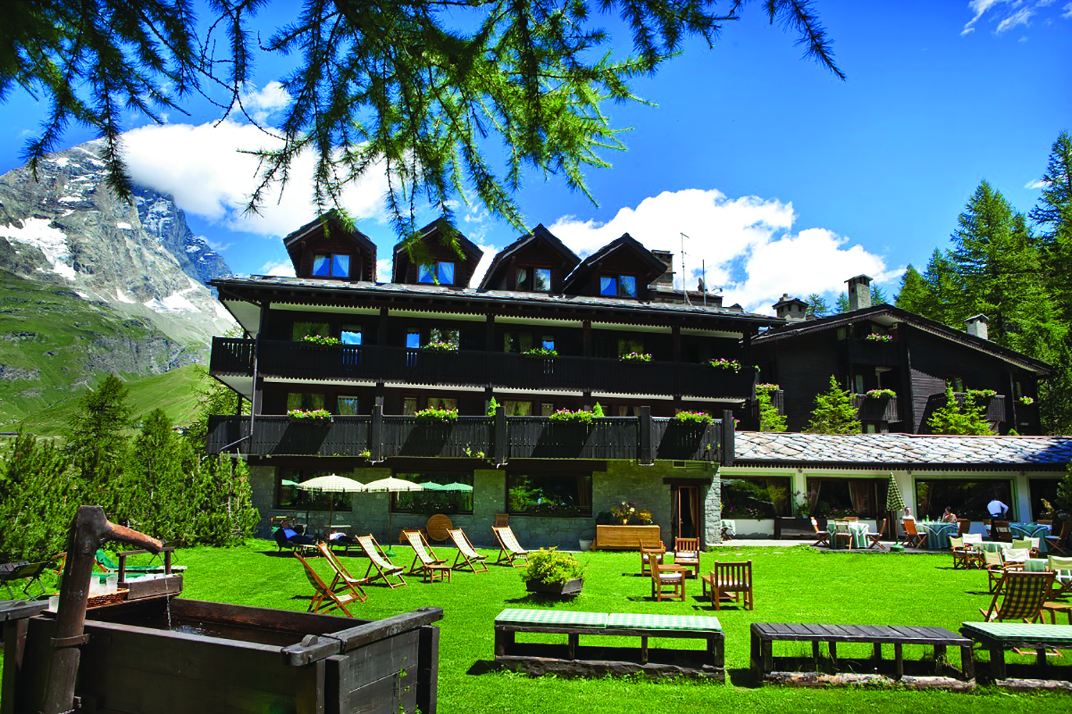 Hotel Hermitage Italy Alps exterior  green lawn out door seating mountain in background