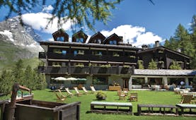 Hotel Hermitage Italy Alps exterior  green lawn out door seating mountain in background