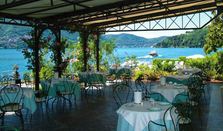 Restaurant with outdoors seating area covered by porch with tables and chairs set up with view of lake 